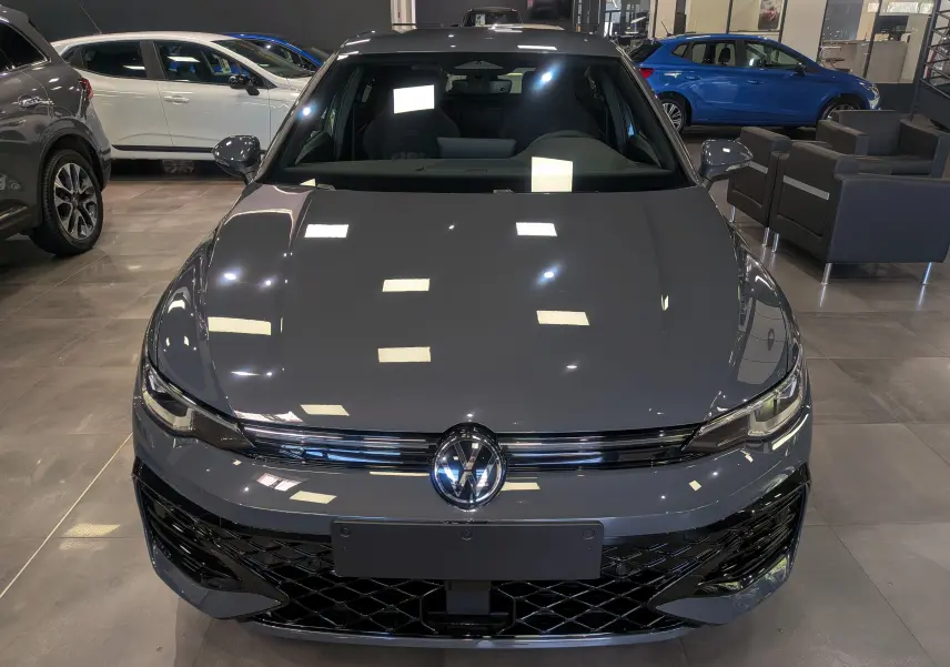 Vue avant d'une Volkswagen Golf VIII gris Urano en finition R-Line Edition, avec calandre noire et logo VW brillant.