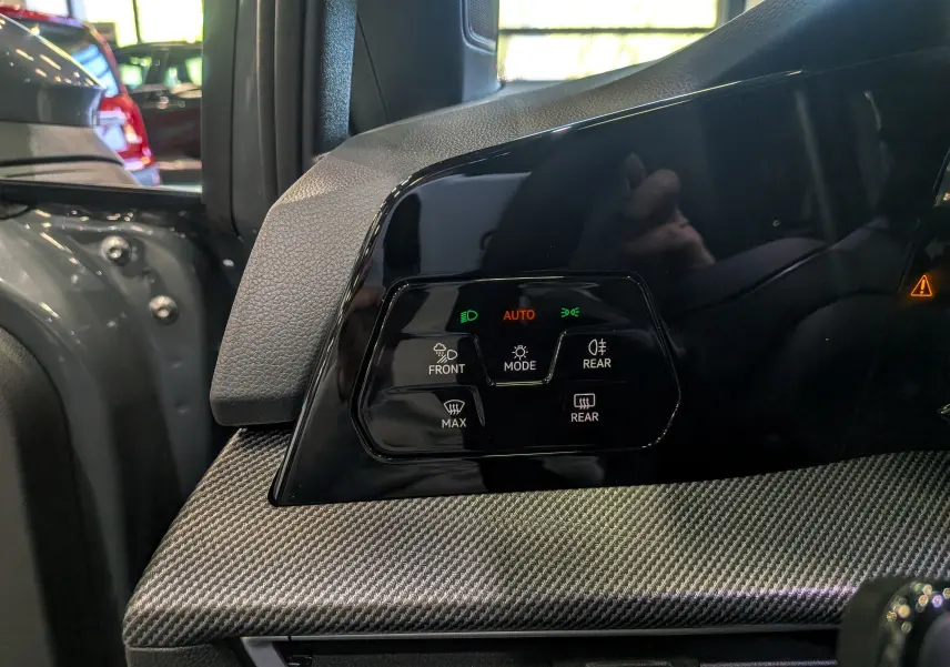 Gros plan sur le panneau de commande des phares et dégivrage, intérieur noir et gris de la Volkswagen Golf VIII R-Line.