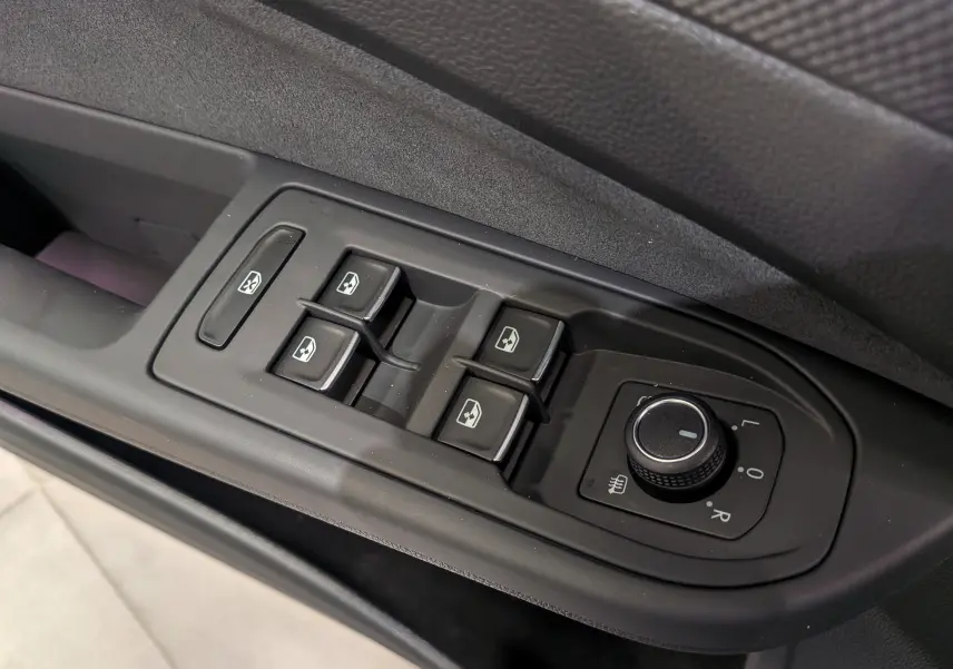 Gros plan sur les commandes de lève-vitres et rétroviseurs côté conducteur de la Volkswagen Golf VIII gris Urano.