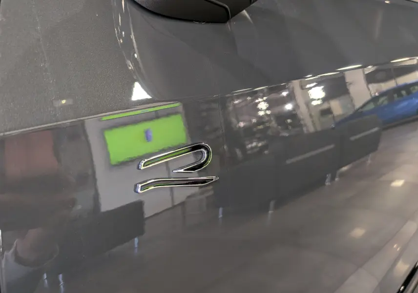 Gros plan sur l’inscription R sur la portière grise Urano d’une Volkswagen Golf VIII hybride en intérieur.