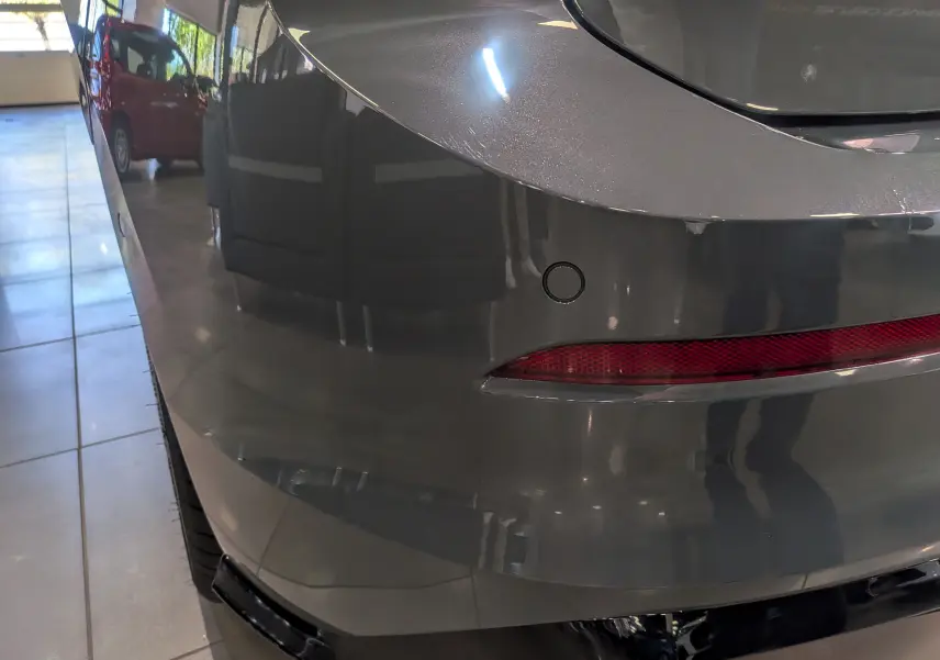 Gros plan sur l’angle arrière droit d’une Volkswagen Golf VIII gris Urano, mettant en valeur le feu arrière et le capteur de stationnement.