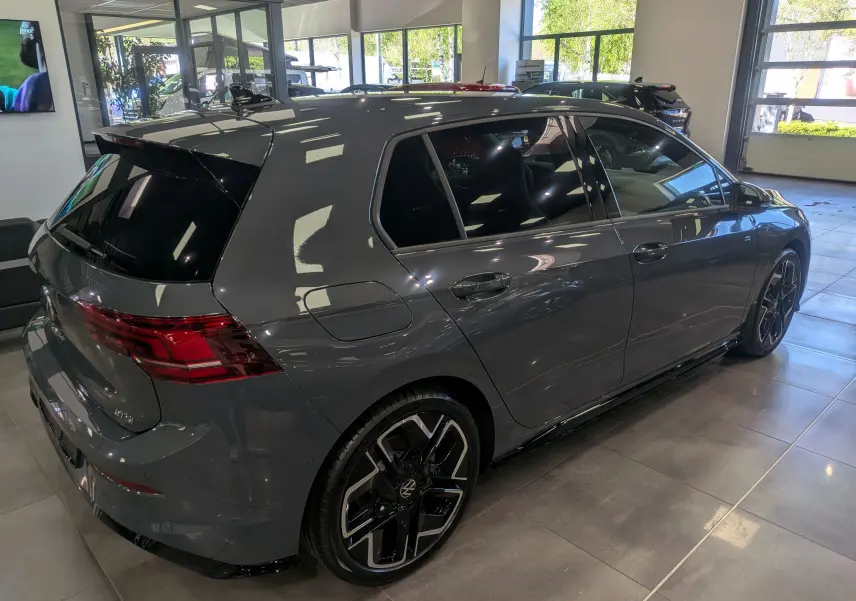 Volkswagen Golf VIII 1.5 eTSI R-Line gris Urano vue 3/4 arrière droit en intérieur, jantes noires bicolores.