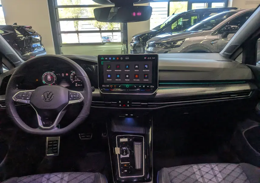 Vue intérieure frontale du tableau de bord de la Volkswagen Golf VIII gris Urano avec écran tactile central et volant multifonction.