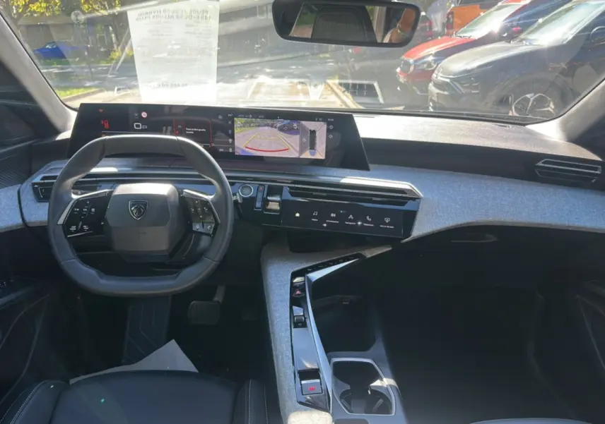 Vue intérieure avant du Peugeot 5008 Hybrid gris artense, avec tableau de bord numérique panoramique et volant cuir multifonctions.