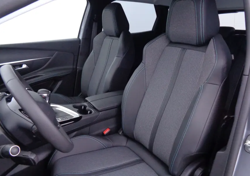 Vue intérieure côté conducteur du Peugeot 3008 2023, sièges en cuir noir et tissu gris avec surpiqûres bleues.