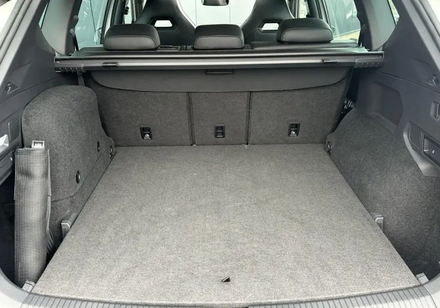 Coffre spacieux du SEAT Tarraco blanc Oryx vu de l'arrière avec banquette arrière et cache-bagages déployé.