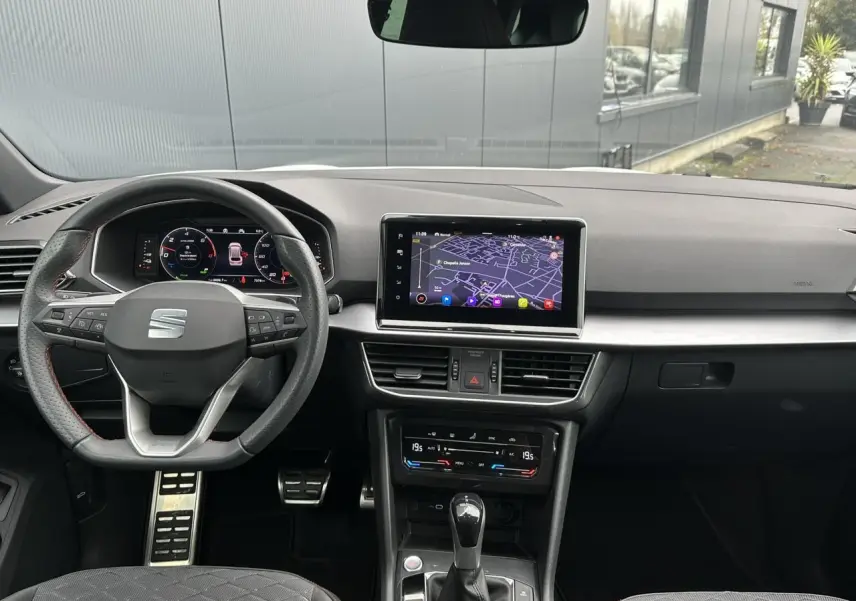 Vue intérieure du tableau de bord du SEAT Tarraco blanc, avec volant sport cuir multifonction et écran tactile navigation.