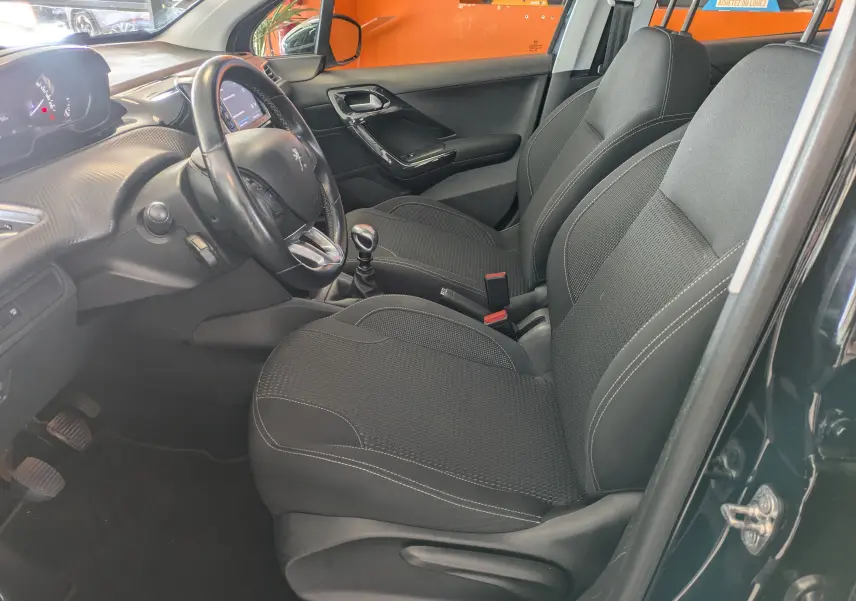 Intérieur avant droit d'une Peugeot 208 Allure noire 2019, sièges tissu noirs et volant multifonction avec boîte manuelle.