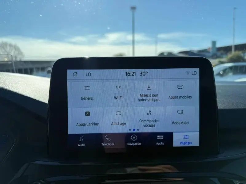 Écran tactile central du Ford Kuga 2024 affichant le menu Réglages avec options connectivité et commandes vocales.