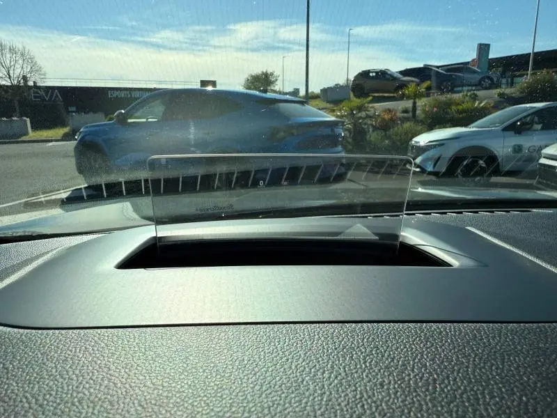 Vue intérieure du tableau de bord avec affichage tête haute transparent, extérieur montrant un Ford Kuga noir en arrière-plan.