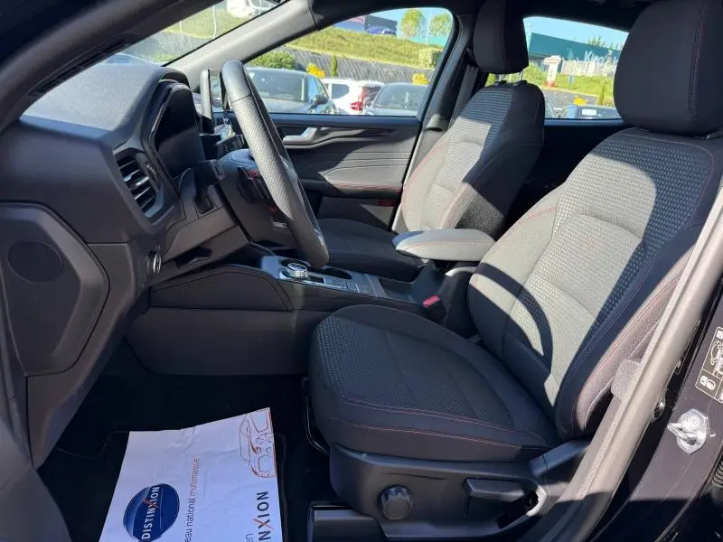 Vue intérieure côté conducteur du Ford Kuga 2.0 EcoBlue 120ch ST-Line 2024, sièges sport tissu noir avec surpiqûres rouges.