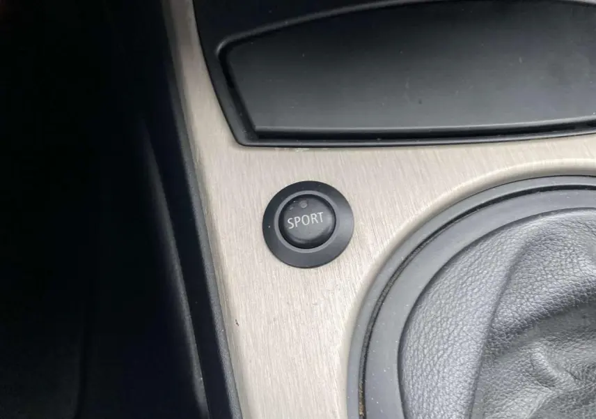 Gros plan sur le bouton sport et le levier de vitesse en cuir dans l’habitacle d’une BMW Z4 Roadster gris clair de 2005.
