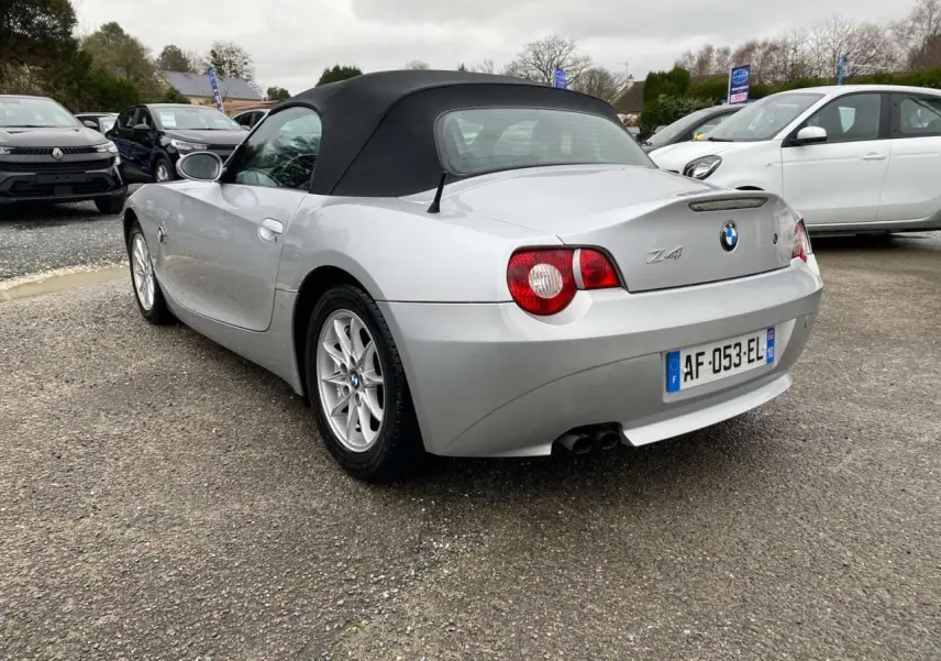 BMW Z4 Roadster gris clair vue 3/4 arrière avec capote noire et double sortie d’échappement visible.