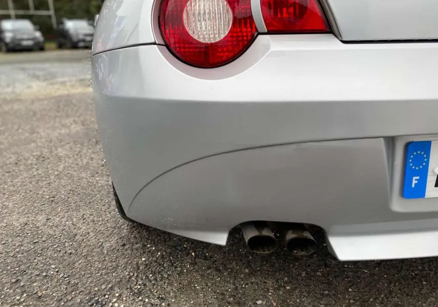 Gros plan sur l'arrière droit d'une BMW Z4 Roadster gris clair, avec double sortie d'échappement et feu arrière rond rouge.