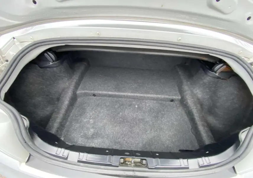 Coffre ouvert d’une BMW Z4 Roadster gris clair de 2005, vue arrière montrant l’espace de rangement vide.