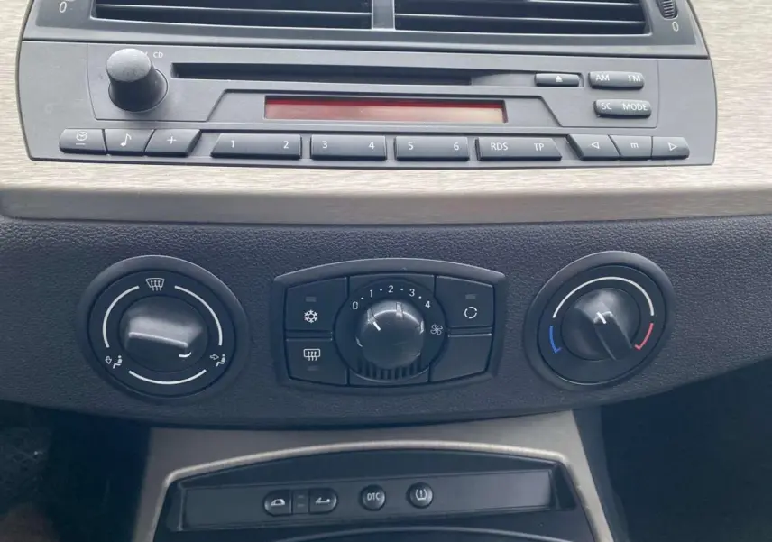 Vue rapprochée de la console centrale d’une BMW Z4 Roadster 2005, montrant les commandes de climatisation manuelle et l’autoradio CD.