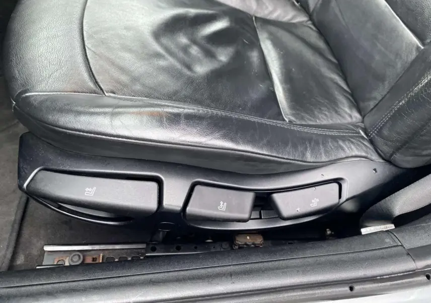 Gros plan sur les commandes de réglage du siège conducteur en cuir noir d'une BMW Z4 Roadster gris clair de 2005.