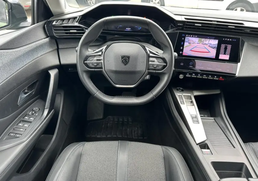 Vue intérieure centrée sur le volant Peugeot 308 2023 avec écran tactile affichant la caméra de recul.