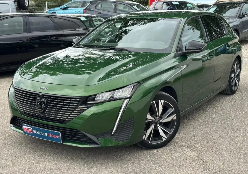 Peugeot 308 vert foncé vue 3/4 avant avec jantes alliage 17 pouces et calandre distinctive noire.