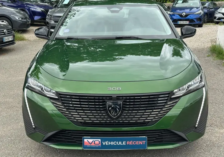 Vue frontale d'une Peugeot 308 2023 vert foncé avec calandre noire et feux LED verticaux distinctifs.