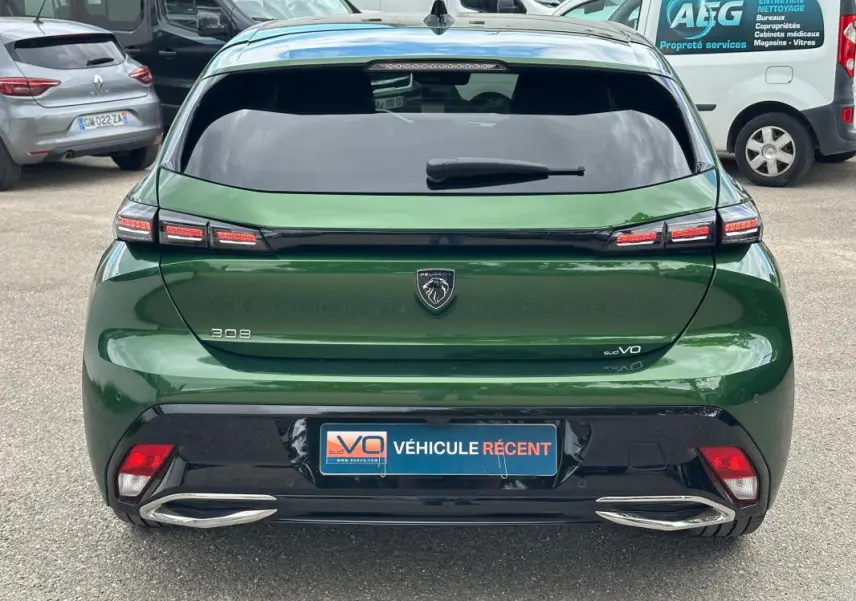Vue arrière d'une Peugeot 308 2023 vert foncé avec feux LED distinctifs et double sortie d'échappement chromée.