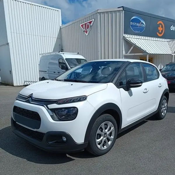 Citroën C3 Société blanche vue 3/4 avant droit, avec rétroviseurs noirs et jantes acier, stationnée devant un bâtiment industriel.