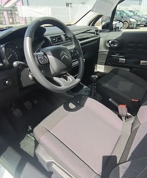 Intérieur de la Citroën C3 Société 2023, vue côté conducteur, volant multifonction et sièges gris visibles.
