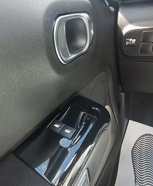 Gros plan sur la commande des vitres électriques et la poignée intérieure côté gauche d’une Citroën C3 Société blanche.