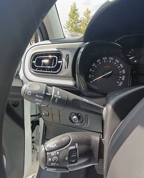 Vue intérieure côté gauche du tableau de bord blanc de la Citroën C3 Société 2023 avec commandes au volant et compteur.