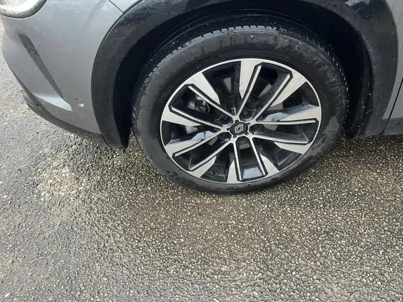 Gros plan sur la roue avant gauche avec jante alliage noire et argentée du Renault Austral blanc 2023