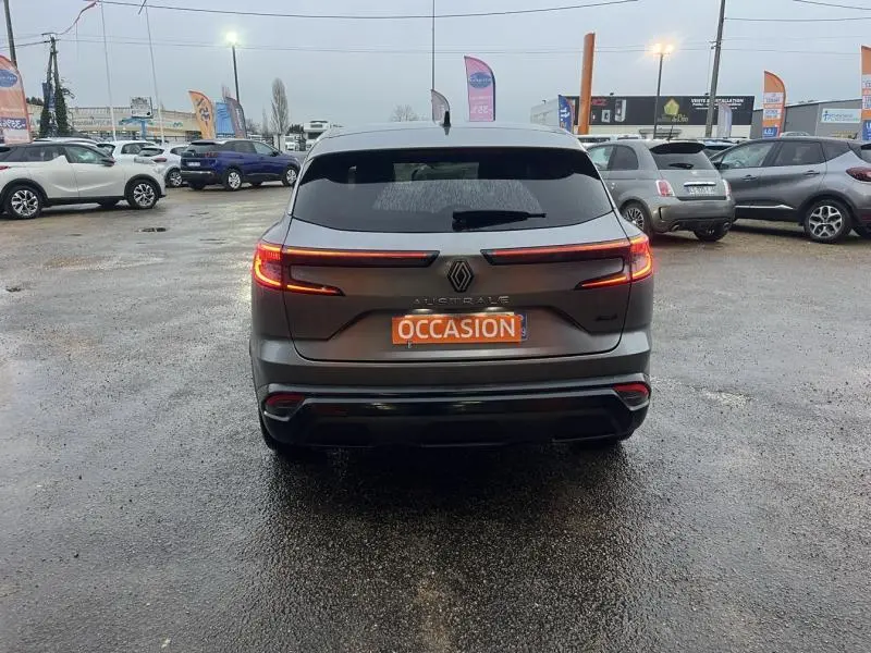 Vue arrière d'un Renault Austral gris avec feux LED allumés sur un parking extérieur en fin de journée.
