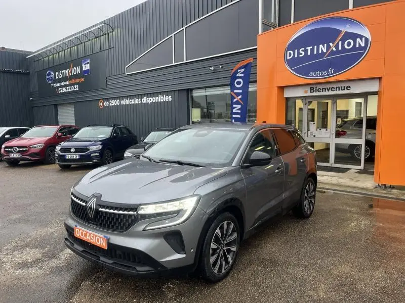 Vue 3/4 avant d'un Renault Austral gris métallisé stationné devant un concessionnaire Distinxion.