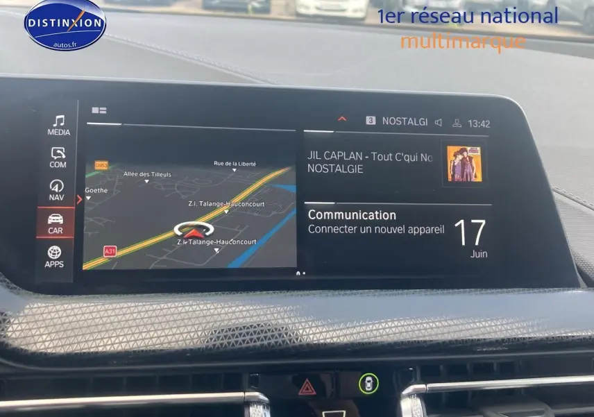 Écran central du BMW Série 1 118i 2023 affichant navigation et musique, intérieur noir moderne avec textures géométriques.