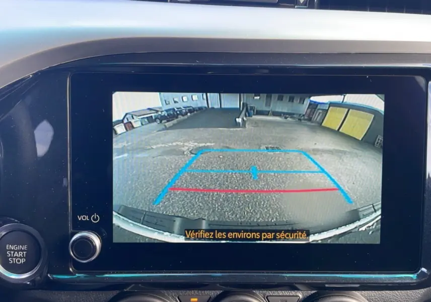 Écran multimédia du Toyota Hilux 2025 affichant la caméra de recul avec lignes de guidage en bleu et rouge.
