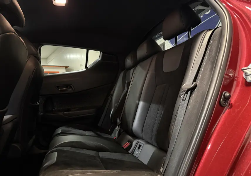 Vue intérieure côté droit des sièges arrière en cuir noir du Toyota C-HR Hybride rouge, porte arrière ouverte.