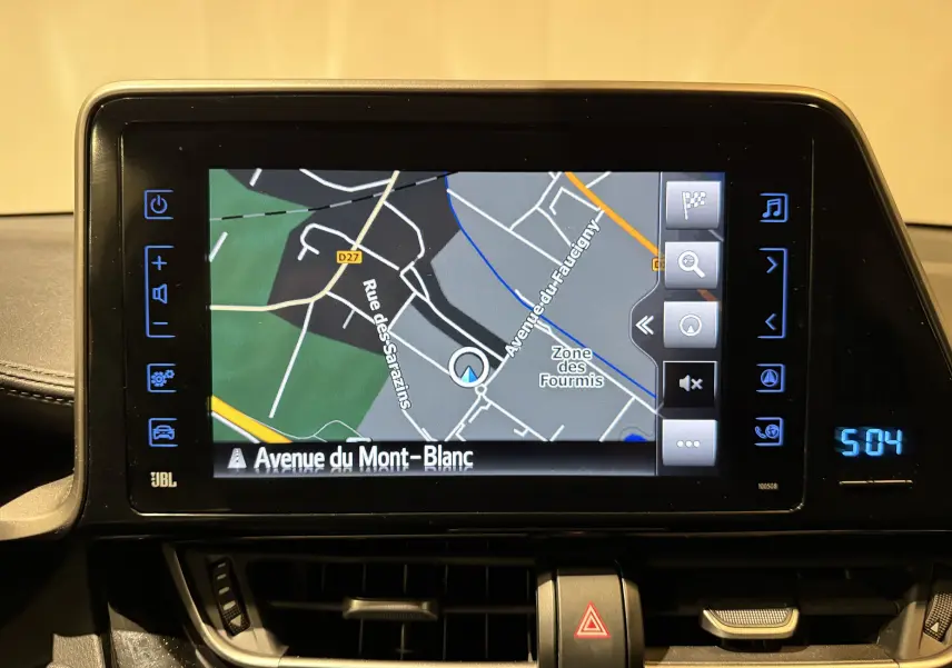 Écran central tactile du Toyota C-HR Hybride 2018 affichant la navigation GPS avec carte et commandes latérales.