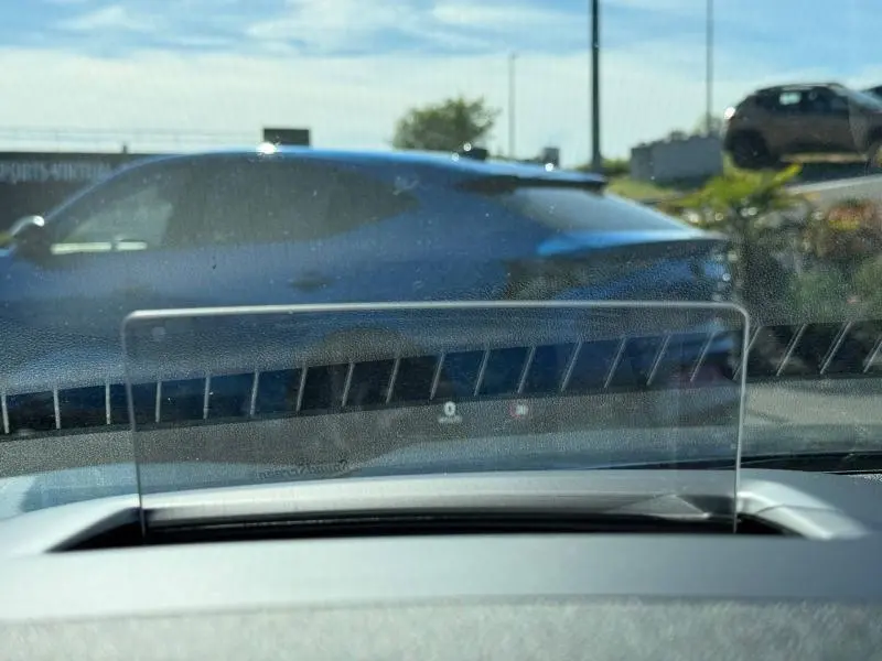 Vue latérale gauche d'un Ford Kuga 2024 bleu Abysse visible à travers le pare-brise avec affichage tête haute au premier plan.