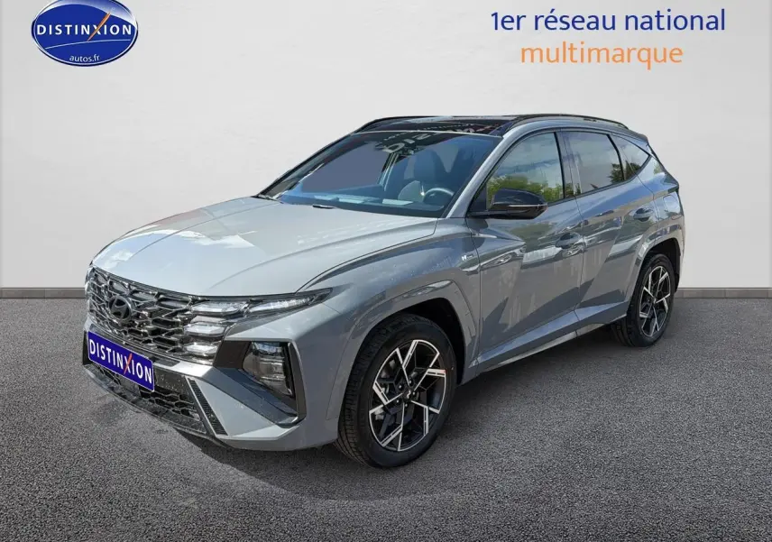 Hyundai Tucson gris shadow en 3/4 avant droit, avec calandre chromée et jantes alu distinctives.