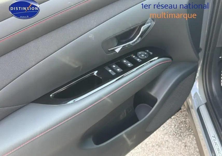 Gros plan sur la porte avant gauche grise du Hyundai Tucson 2026, avec commandes de vitres et habillage noir mat.