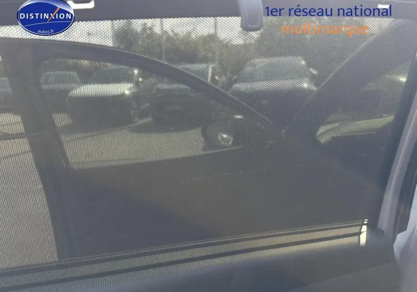 Vue intérieure côté gauche du Hyundai Tucson gris shadow avec pare-soleil en filet et rétroviseur extérieur visible.