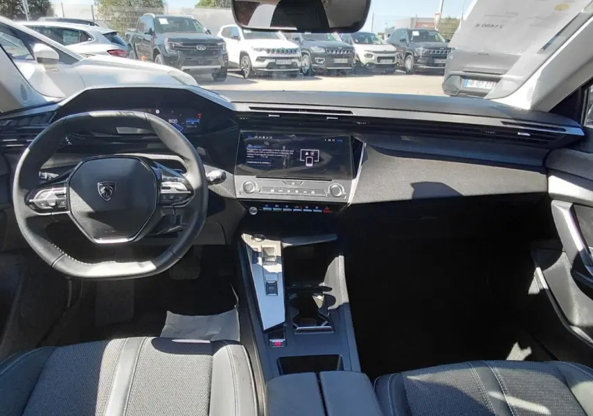 Vue intérieure avant du Peugeot 308 gris 2025, mettant en valeur le volant compact et le cockpit numérique moderne.
