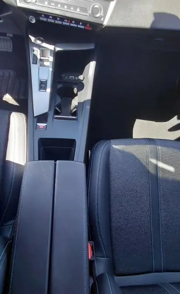 Vue plongeante sur la console centrale et siège avant gris foncé de la Peugeot 308 BlueHDi 130ch avec accoudoir central et écran tactile.