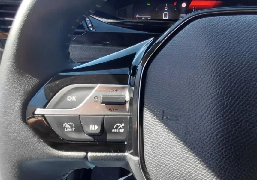 Gros plan sur le volant noir de la Peugeot 308 2025, montrant les commandes du régulateur et le logo lion au centre.