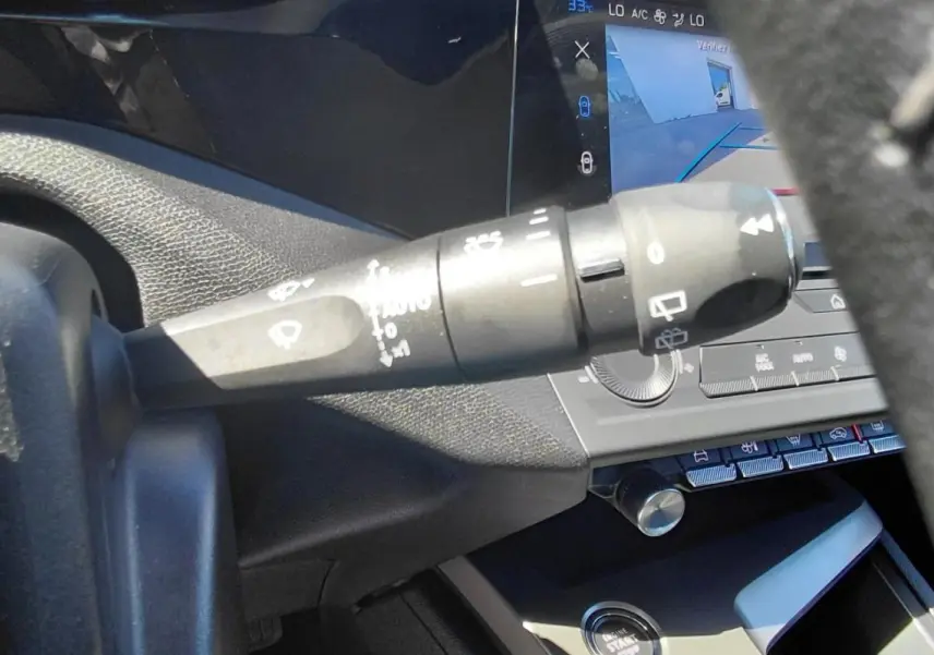 Gros plan sur la commande d’essuie-glace à gauche du volant dans l’habitacle d’une Peugeot 308 gris 2025.