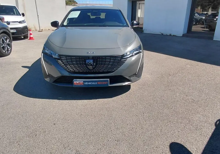 Peugeot 308 gris vue de face, mettant en valeur sa calandre moderne et ses phares fins en extérieur.