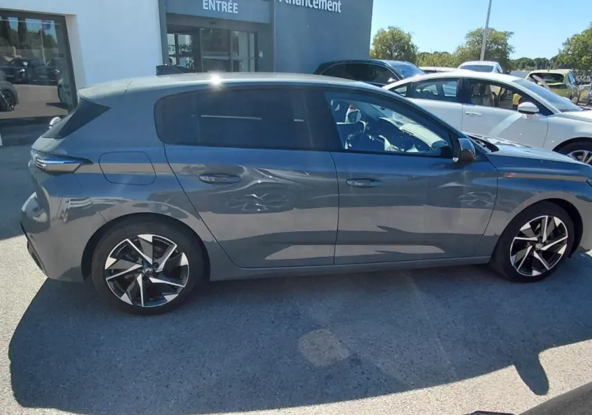 Vue de profil côté droit d'une Peugeot 308 gris métallisé garée en extérieur, avec jantes alliage distinctives.