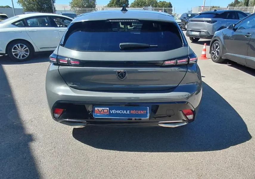 Vue arrière d'une Peugeot 308 gris métallisé 2025 avec feux LED et double sortie d'échappement visible en extérieur.