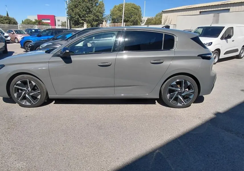 Peugeot 308 gris vue de profil côté gauche, avec jantes alliage et vitres teintées, stationnée en extérieur.