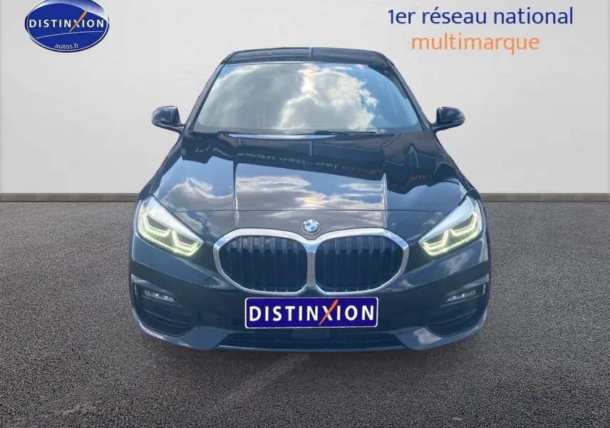 Vue frontale d'une BMW Série 1 noire avec phares LED allumés et calandre double haricot chromée.