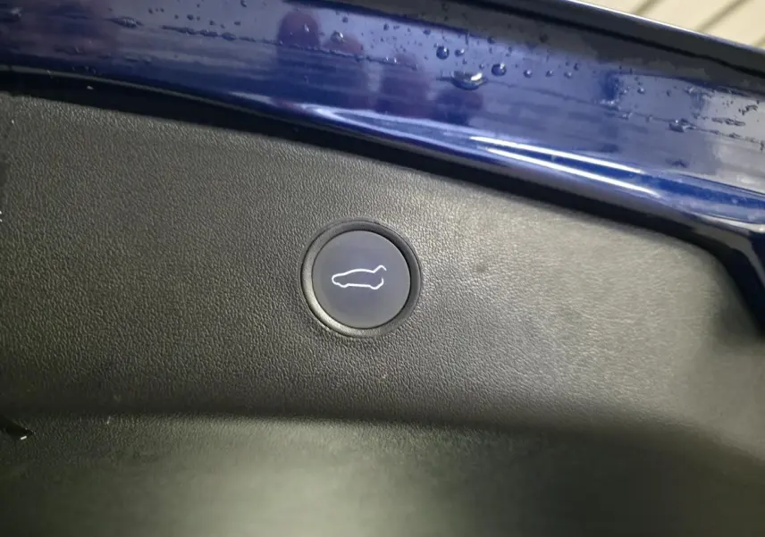Bouton d'ouverture du coffre sur la partie intérieure du hayon bleu foncé d'une Tesla Model 3 RWD 2021.